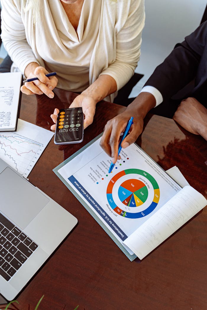 Home Two business professionals discussing financial documents and strategies at an office desk.
